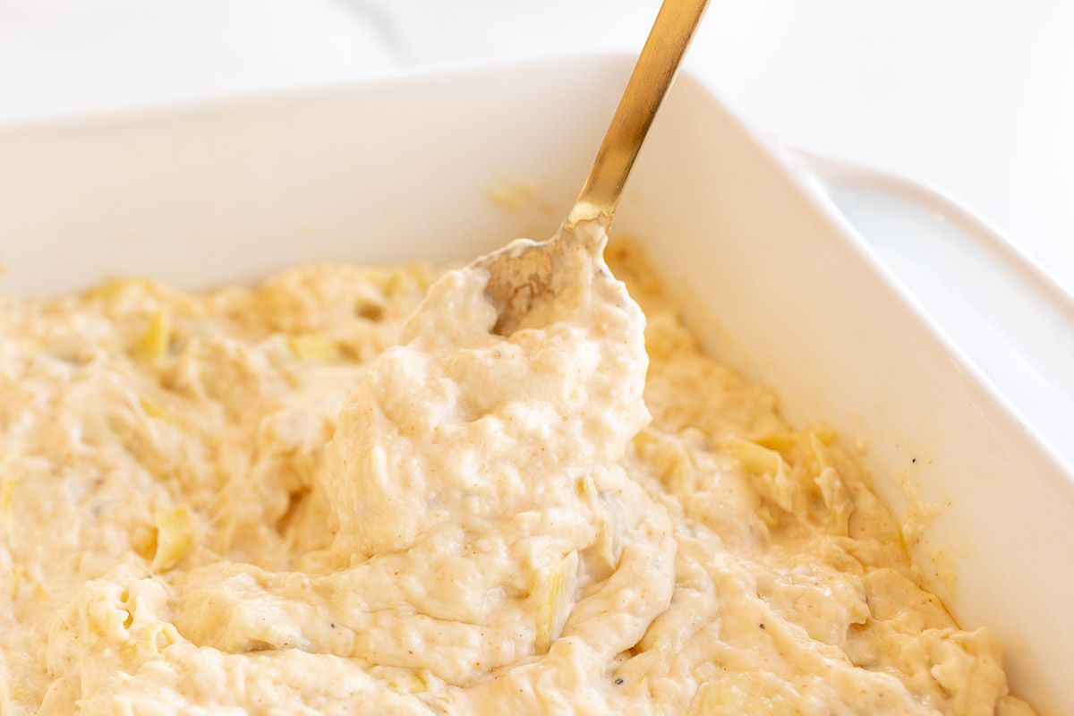 A square baking dish full of artichoke dip