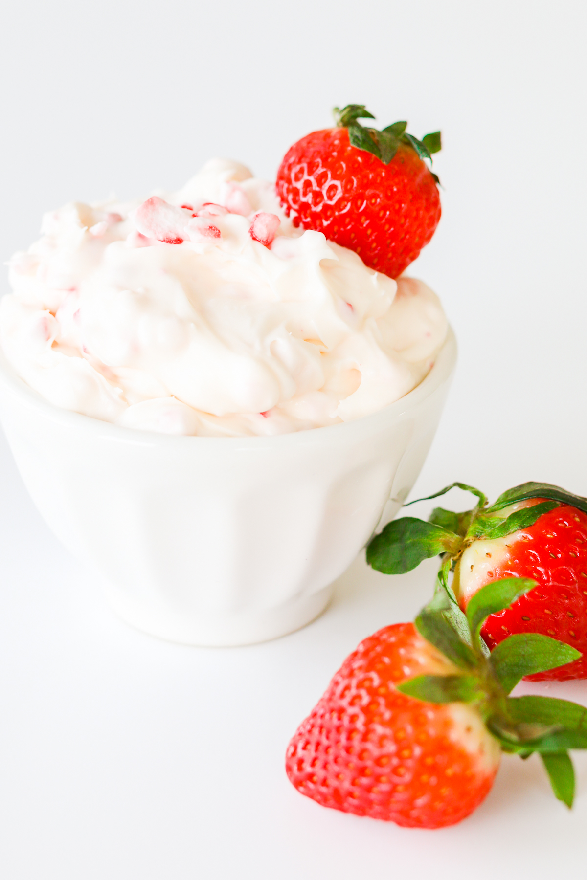A white bowl with strawberries and a sweet dip.