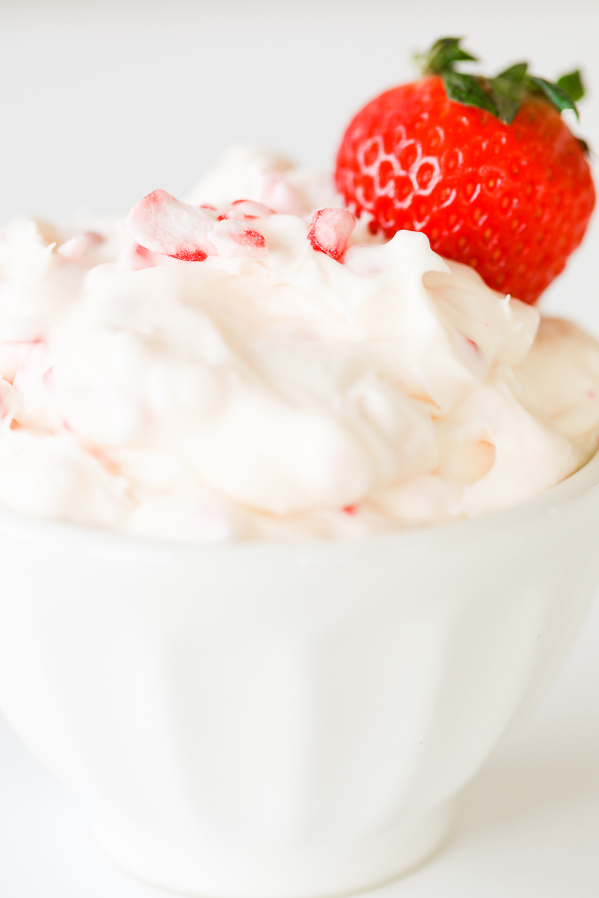 A white bowl with whipped cream and a sweet dip.