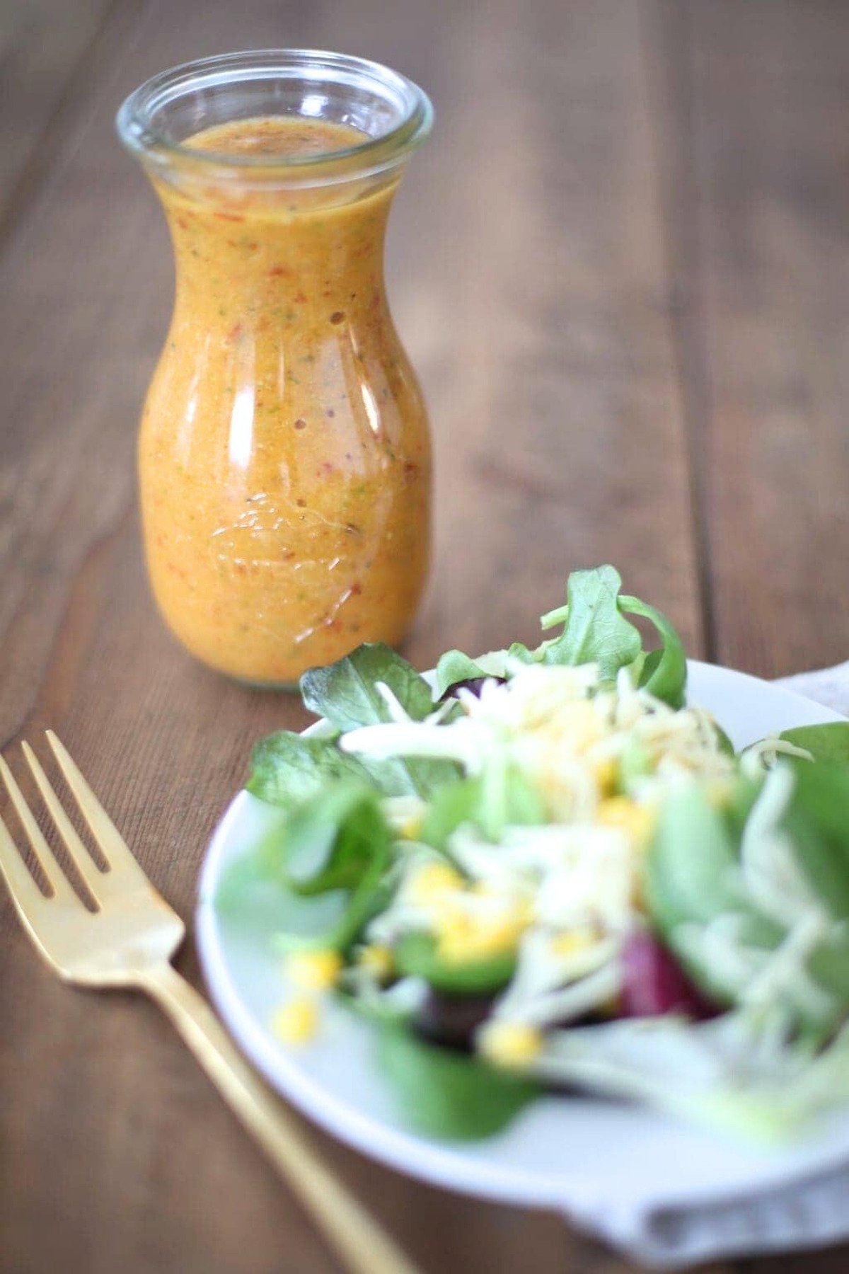 A plate with a salad and a jar of chipotle vinaigrette.