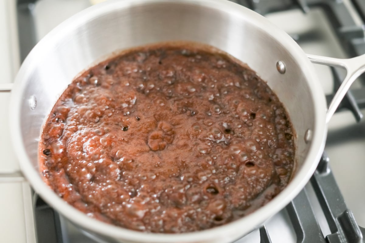 A pot of chocolate sauce simmering on a stove top, perfect for making chocolate no bake cookies or preacher cookies.