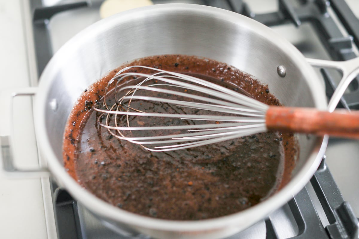 A pot with a whisk in it on top of a stove, preparing preacher cookies.