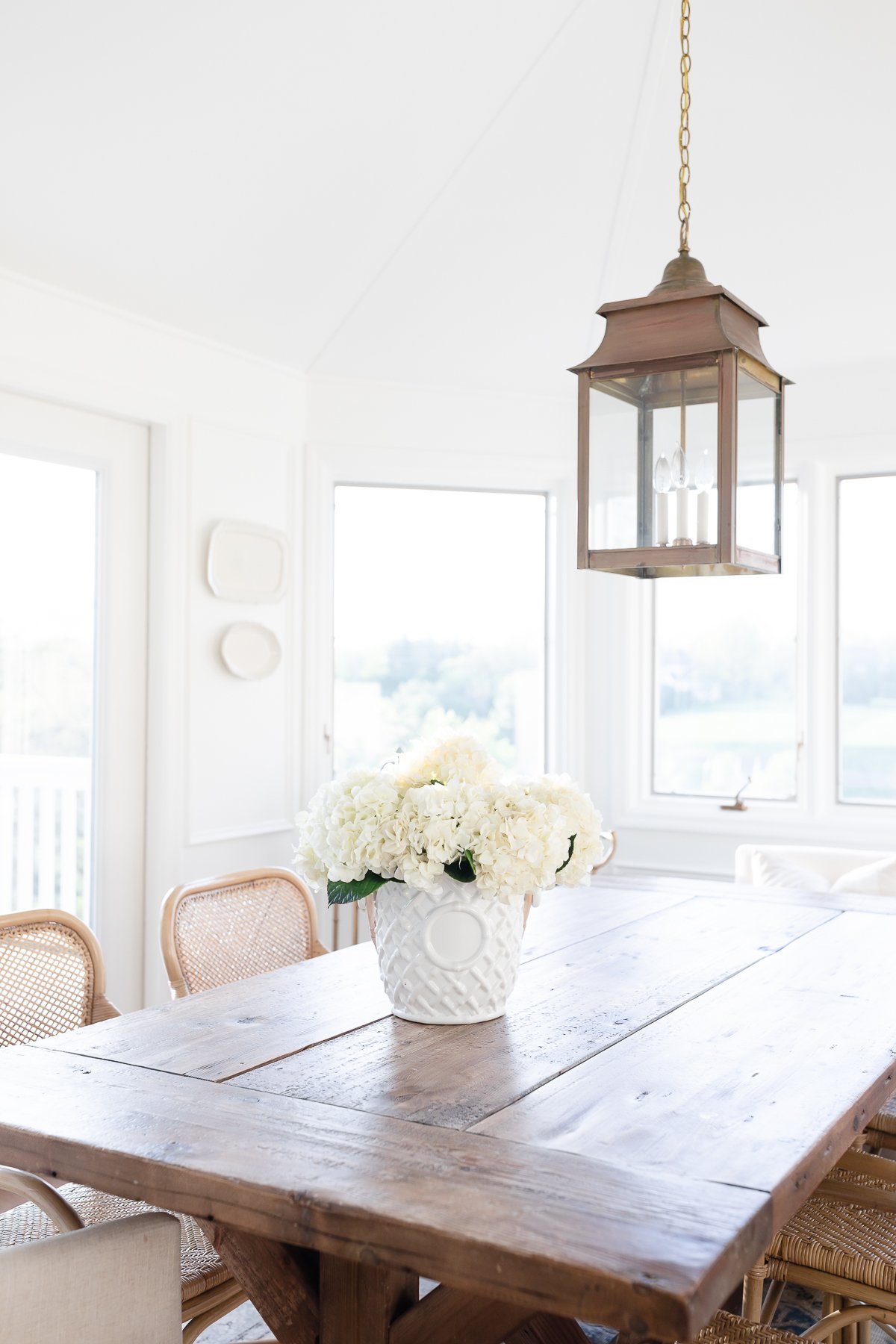 A Restoration Hardware dining table with rattan chairs.