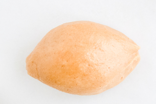 A ball of dough resembling peanut butter truffles on a white surface.