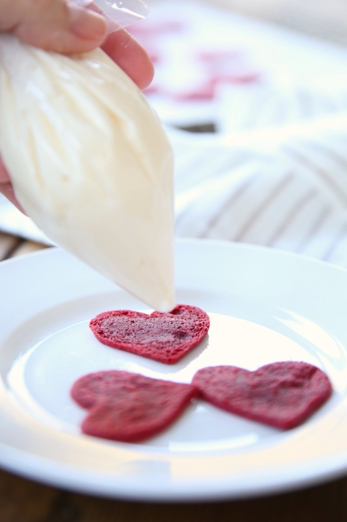A person is putting homemade red velvet cookies on a plate.