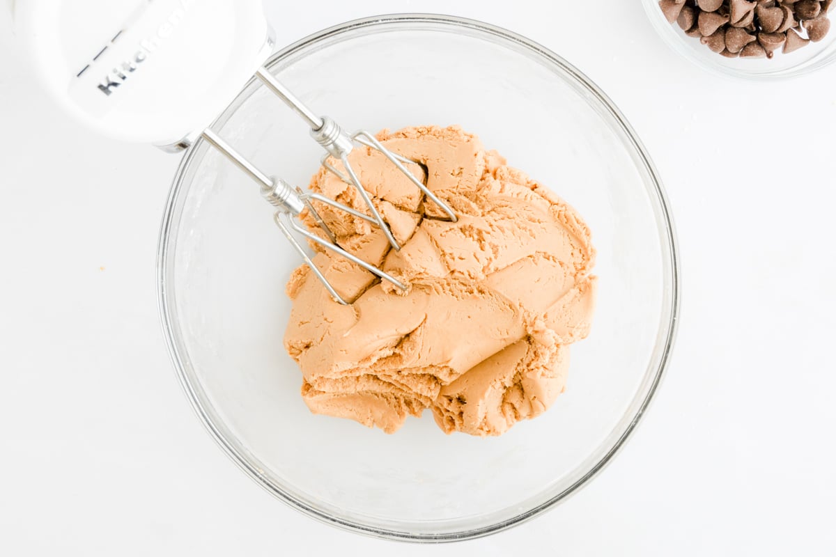 A bowl with a mixer and a bowl of peanut butter truffles.