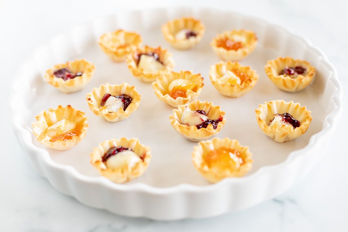 Brie bites topped with jam on a white platter