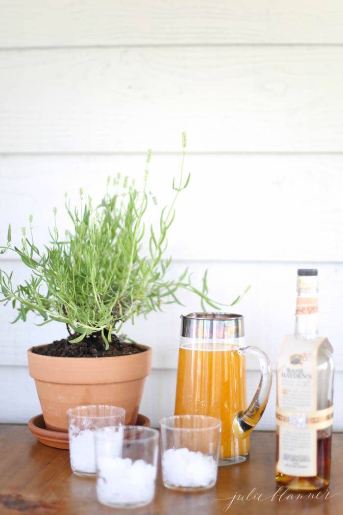 A pitcher of orange drink next to three ice filled glasses
