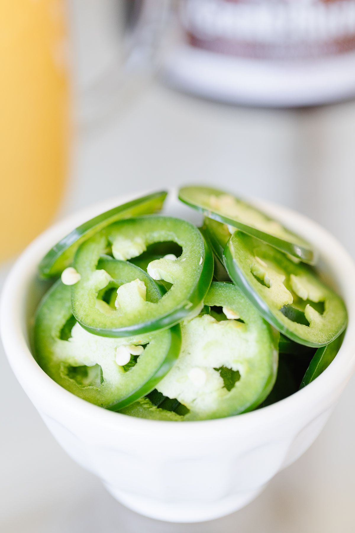 A white bowl of sliced jalapenos
