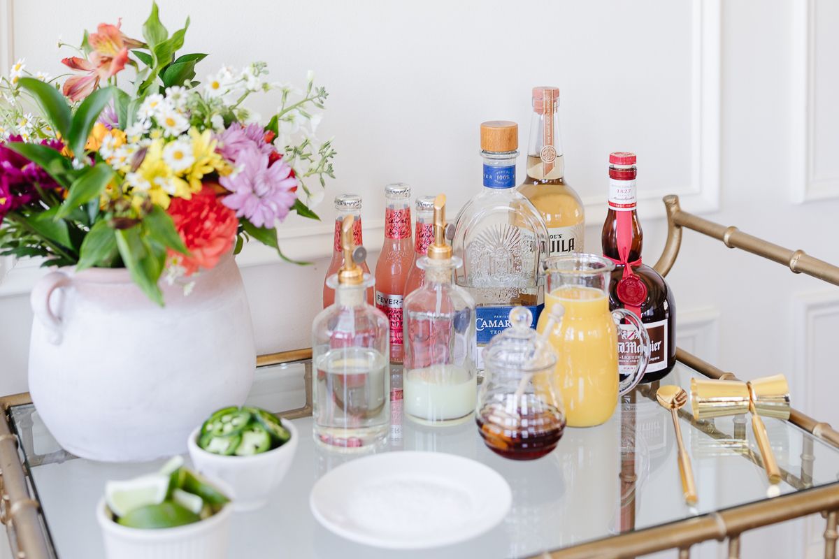 Ingredients for a margarita bar set up on a gold cart