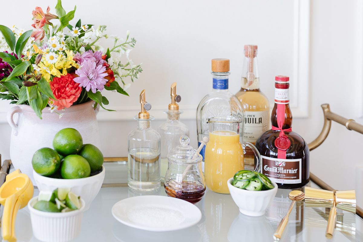 Ingredients for a margarita bar set up on a gold cart