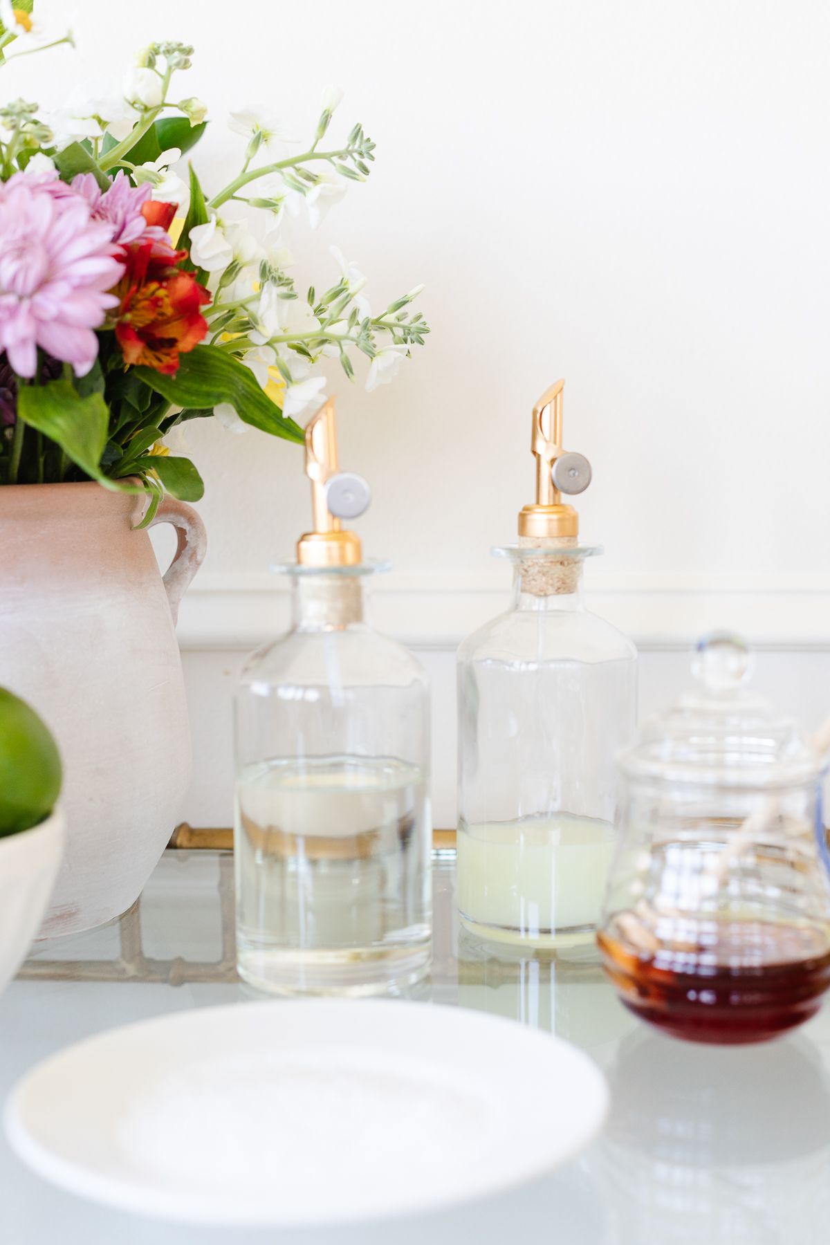 Simple syrup, lime juice and honey on a gold bar cart