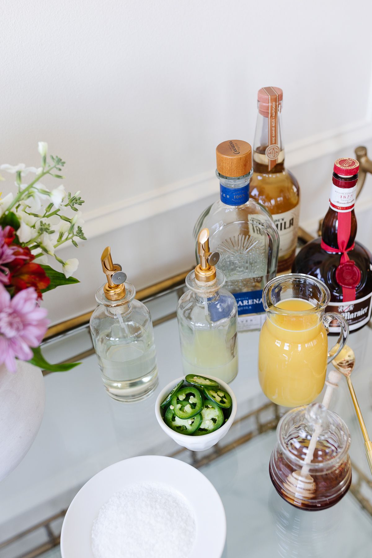 Ingredients for a margarita cocktail set up on a gold bar cart