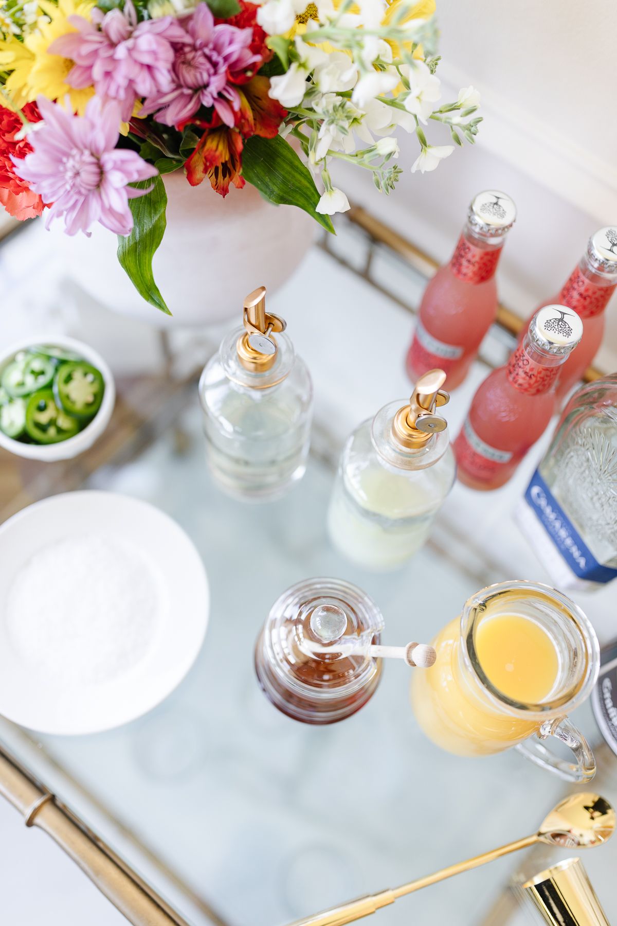 An array of ingredients for a margarita bar on a gold cart