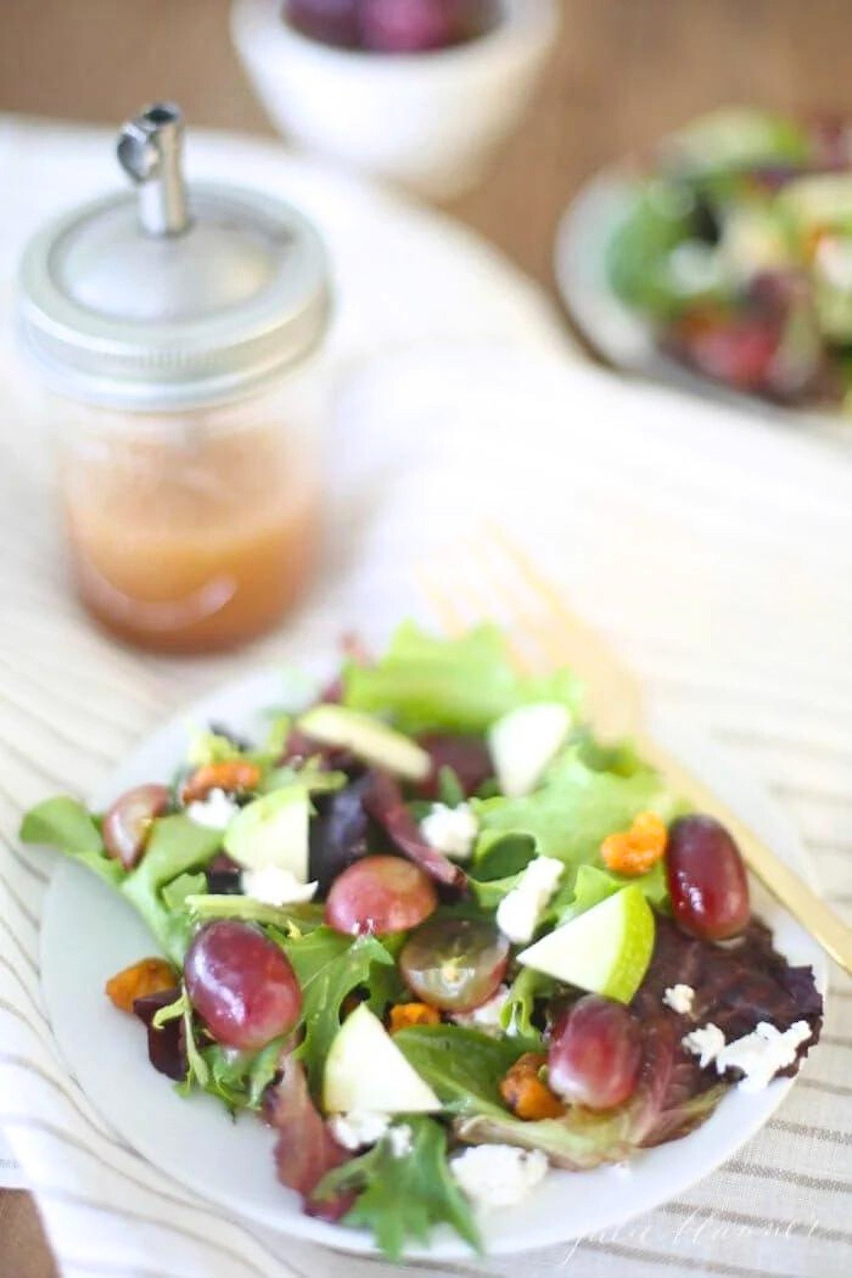 A salad with grapes, walnuts, and raspberry vinaigrette on a plate.