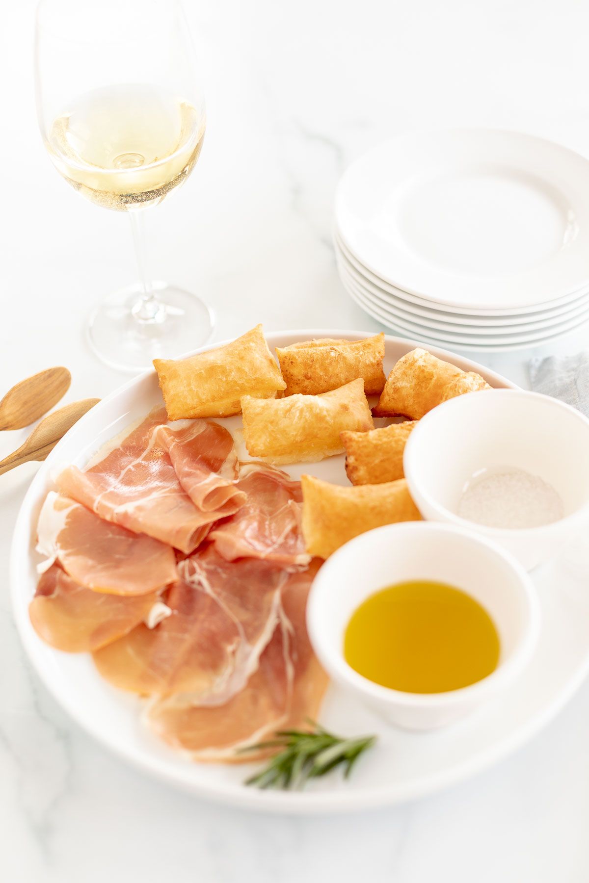 Gnocco fritto on a white plate with bowls of olive oil and sea salt to the side