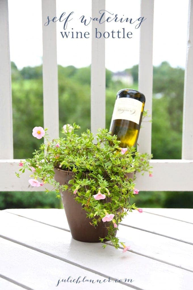 A vase of flowers on a white porch with a wine bottle inside. 