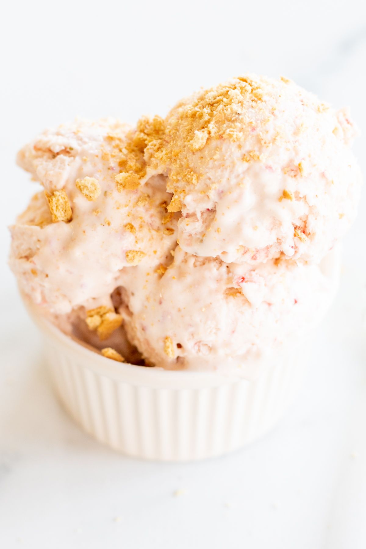 Strawberry cheesecake ice cream in a white bowl.