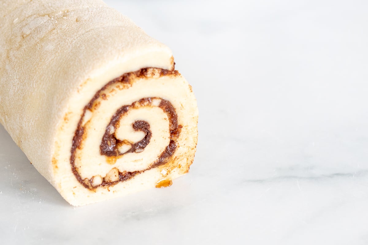 An apple cinnamon roll is sitting on top of a marble table.