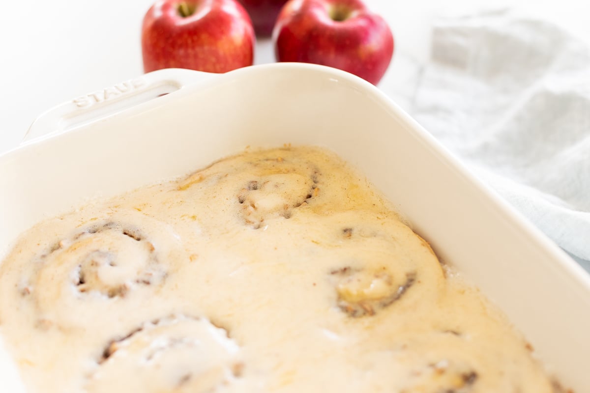 Apple cinnamon rolls in a white baking dish.