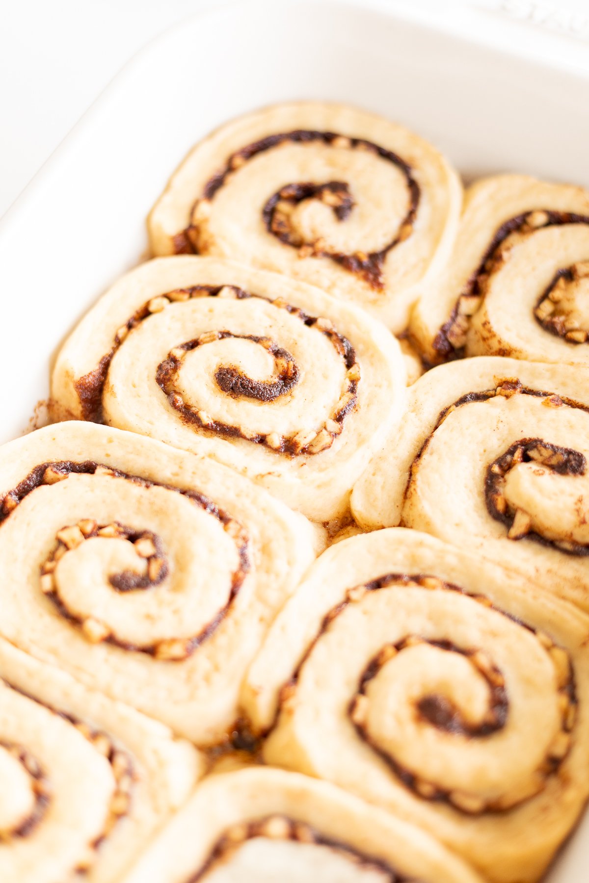 Apple cinnamon rolls in a white baking dish.