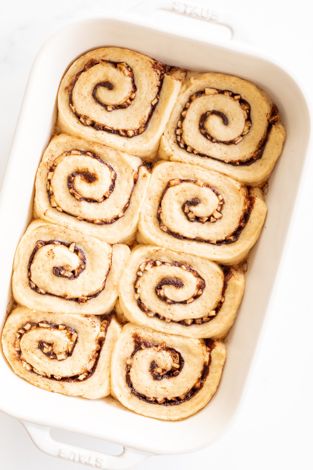 Apple cinnamon rolls in a white baking dish.