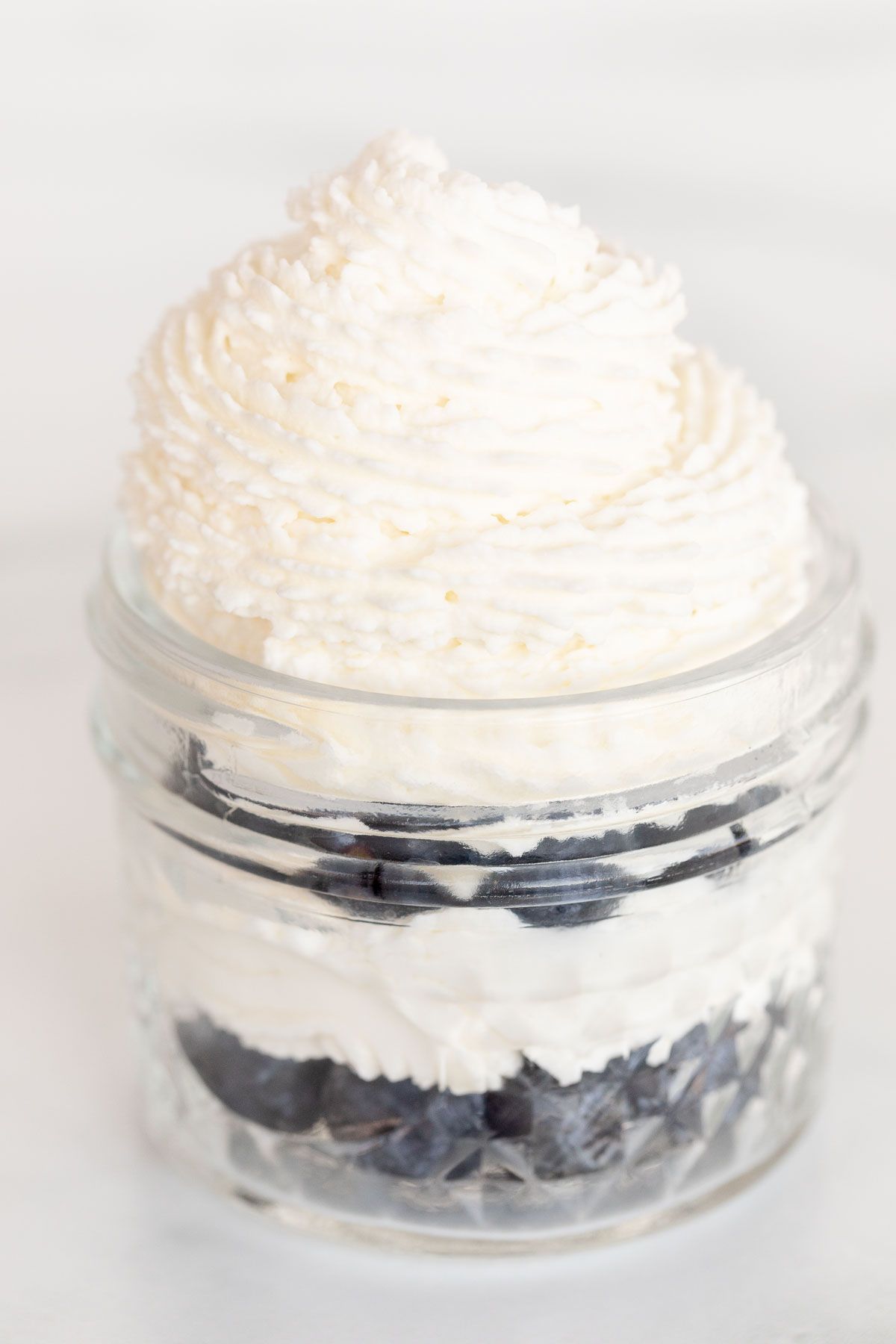 A layered dessert in a jar, topped with mascarpone cream