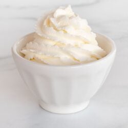 A white bowl full of whipped mascarpone cream on a marble surface.