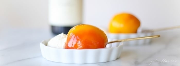 peached peaches in white wine in shallow dishes with mascarpone cream and a gold spoon