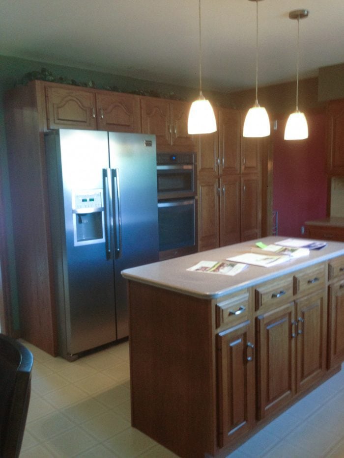 kitchen "before" image featuring dated oak kitchen cabinets and light fixtures