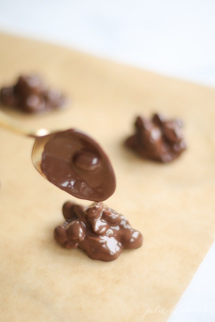 dropping peanut clusters onto parchment paper with a spoon