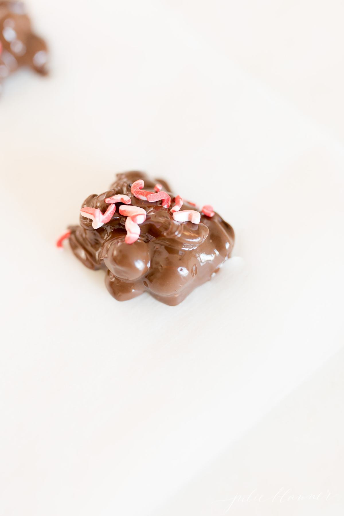 closeup of a peanut cluster on parchment paper with red sprinkles