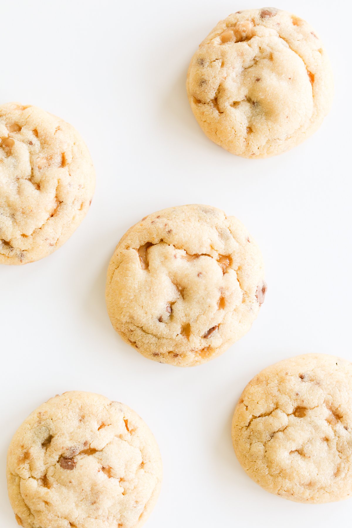 Five toffee cookies on a white surface.