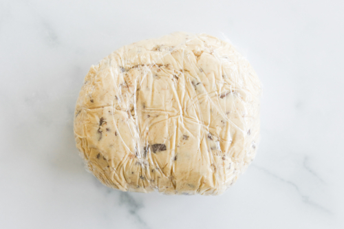 A ball of dough sitting on a marble surface, ready to be shaped into delicious toffee cookies.