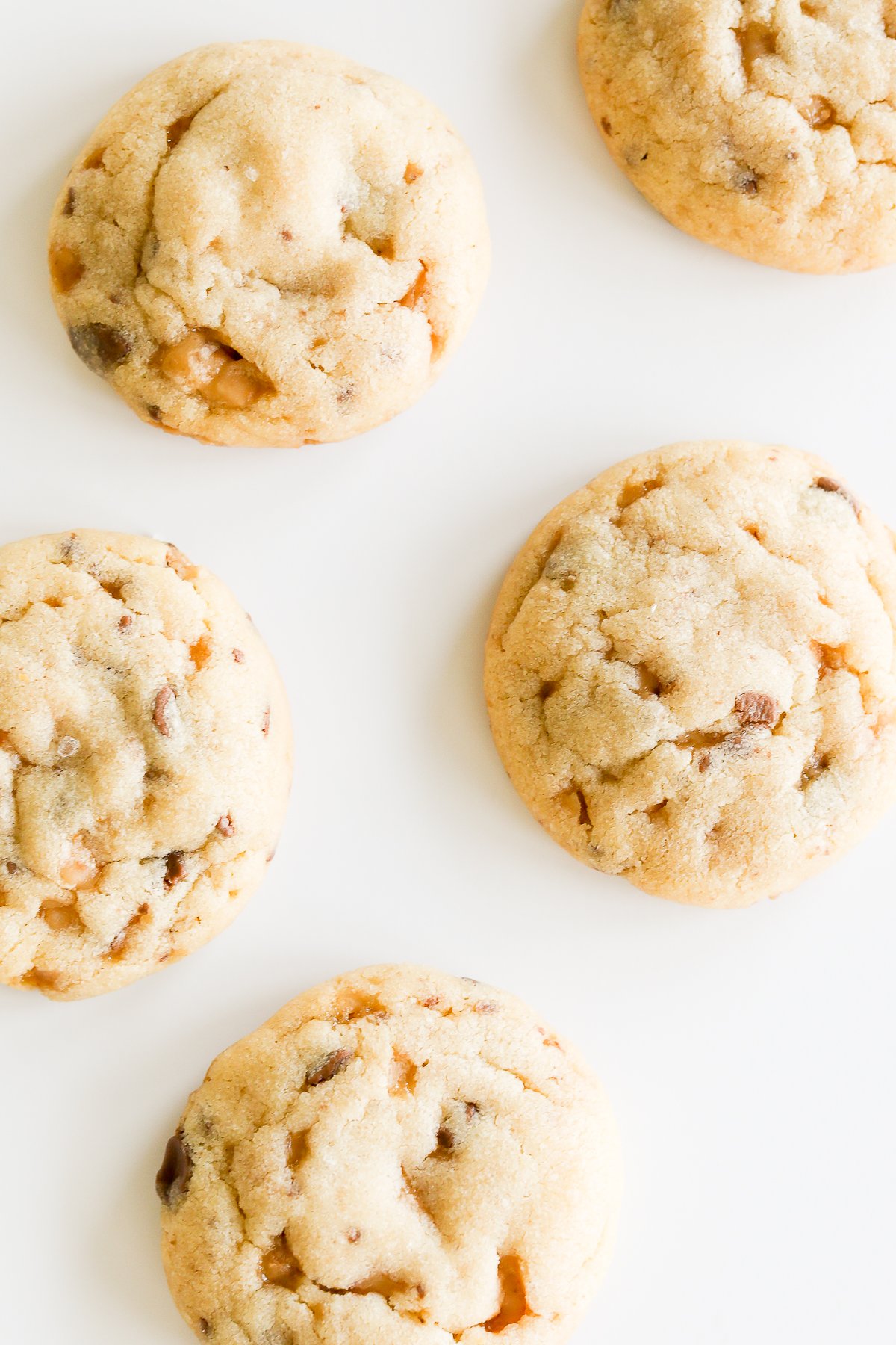 Five toffee cookies on a white surface.