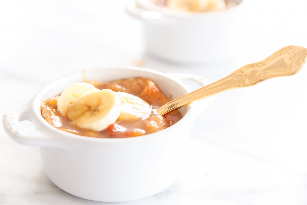 bread pudding in an individual, white baking dishes, topped with sliced bananas.