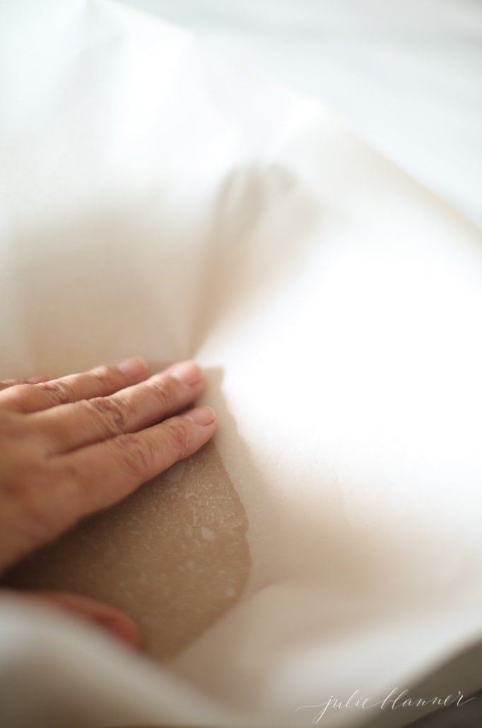 pressing fudge into a pan with parchment paper