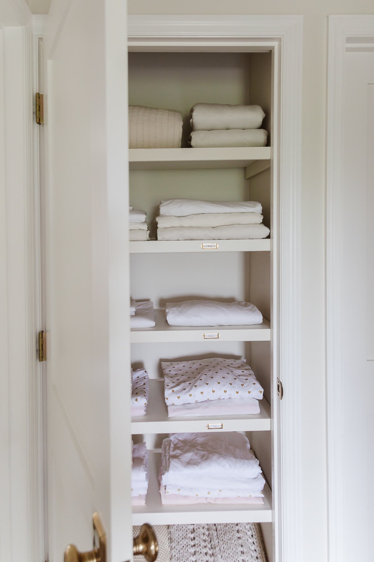 A linen closet filled with white towels and white sheets.