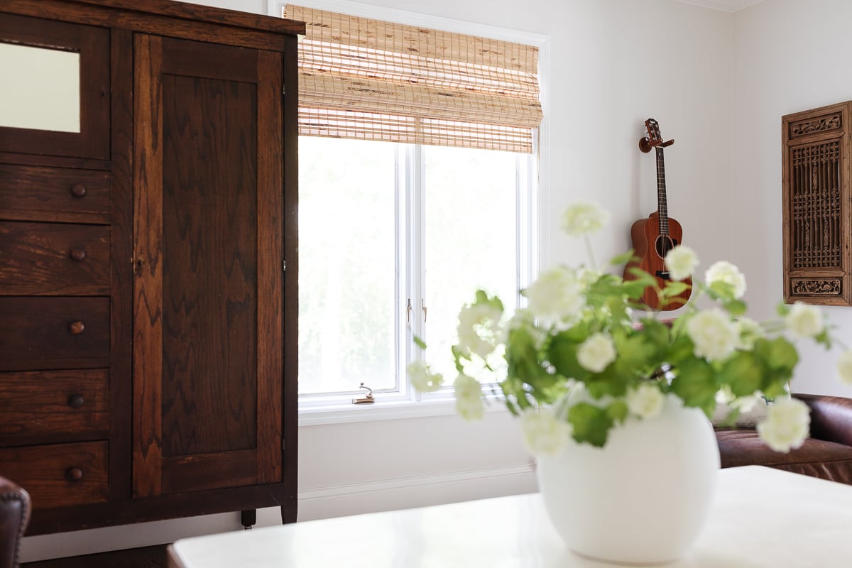 In the music room, there is a vase of flowers on the table and a guitar hanging on the wall in the background.