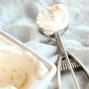 A bowl of homemade vanilla ice cream with a spoon next to it.