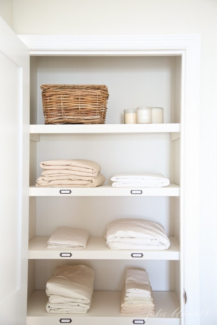 A hallway linen closet organized with bedding etc