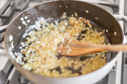 Onions and garlic cooking on a stovetop.