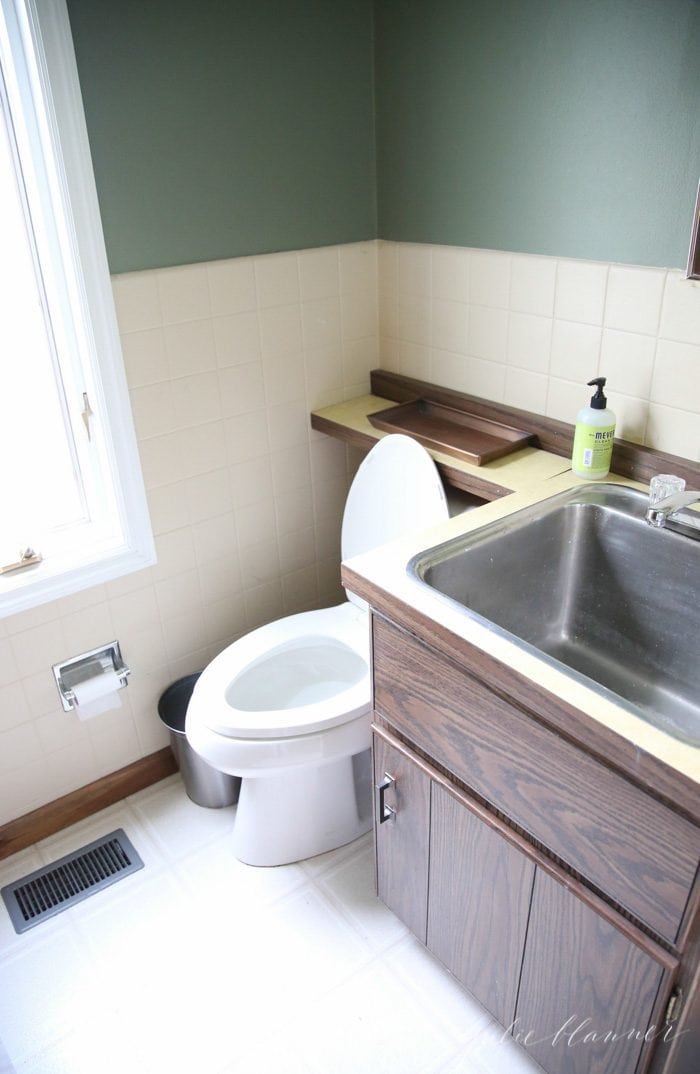 an image of a dated powder room with a large stainless steel sink.