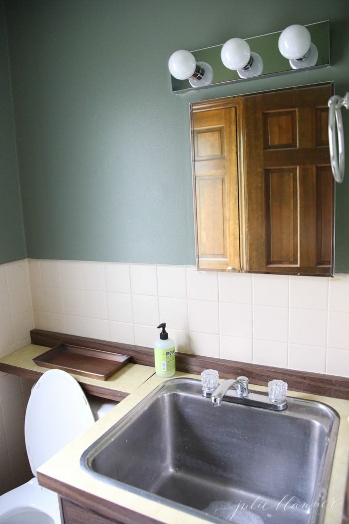 an image of a dated powder room with a large stainless steel sink.