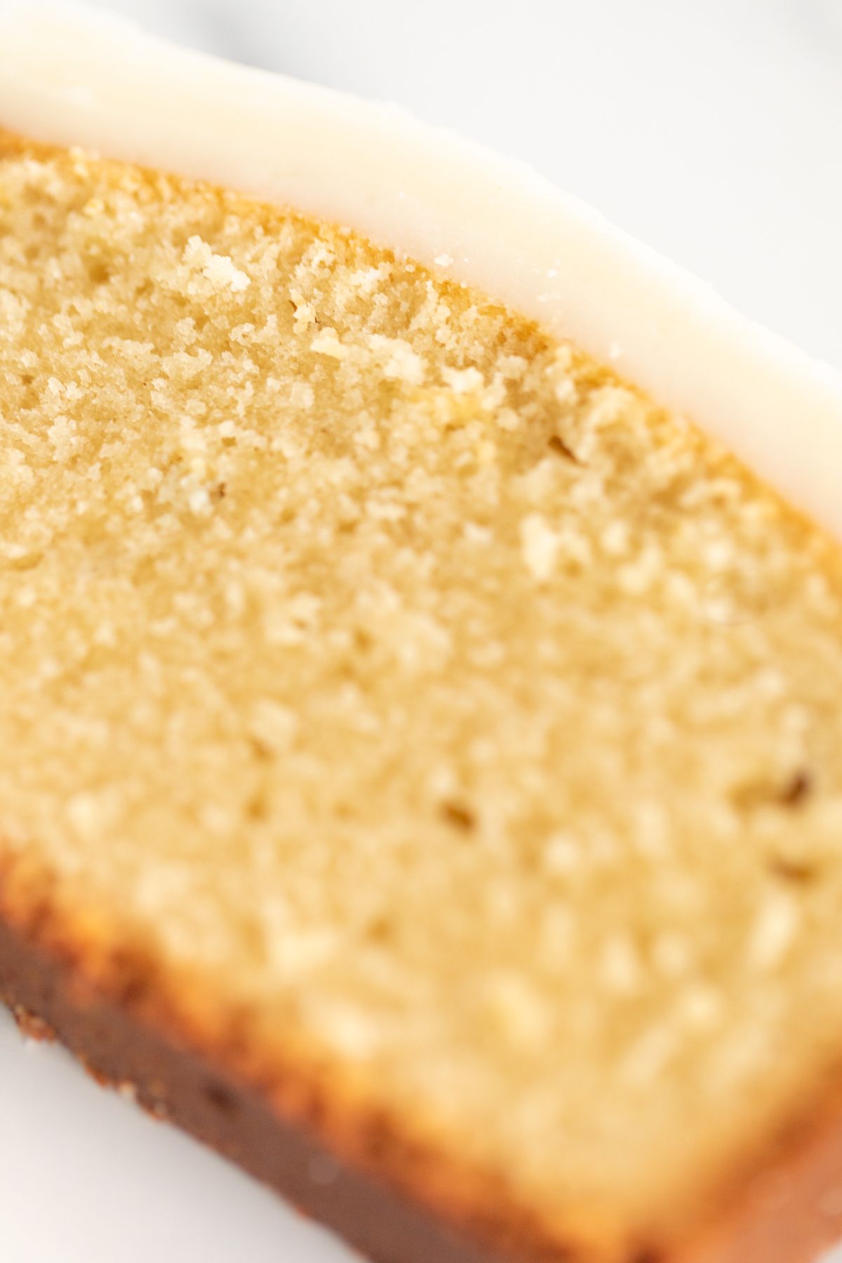 A slice of pound cake on a marble countertop, topped with glaze.