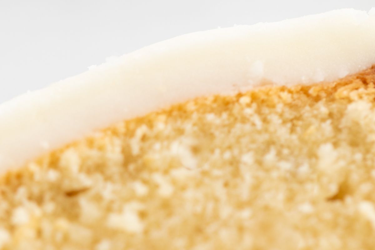 A slice of pound cake on a marble countertop, topped with glaze.