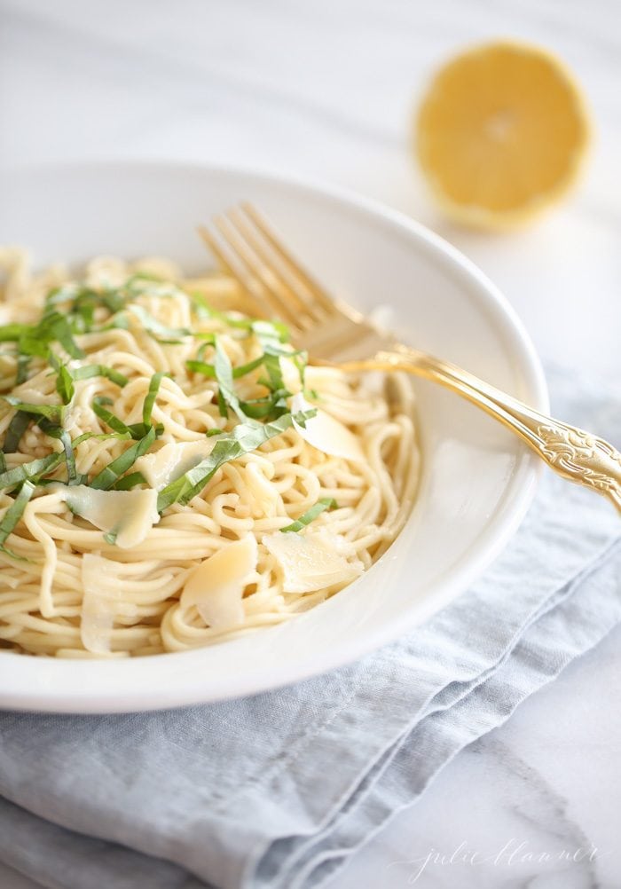 A bowl of spaghetti pasta in white bowl with gold spoon 