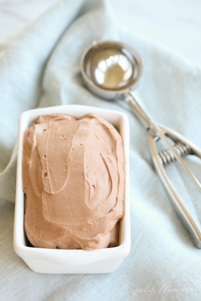 Ice cream in a white loaf pan next to a scoop