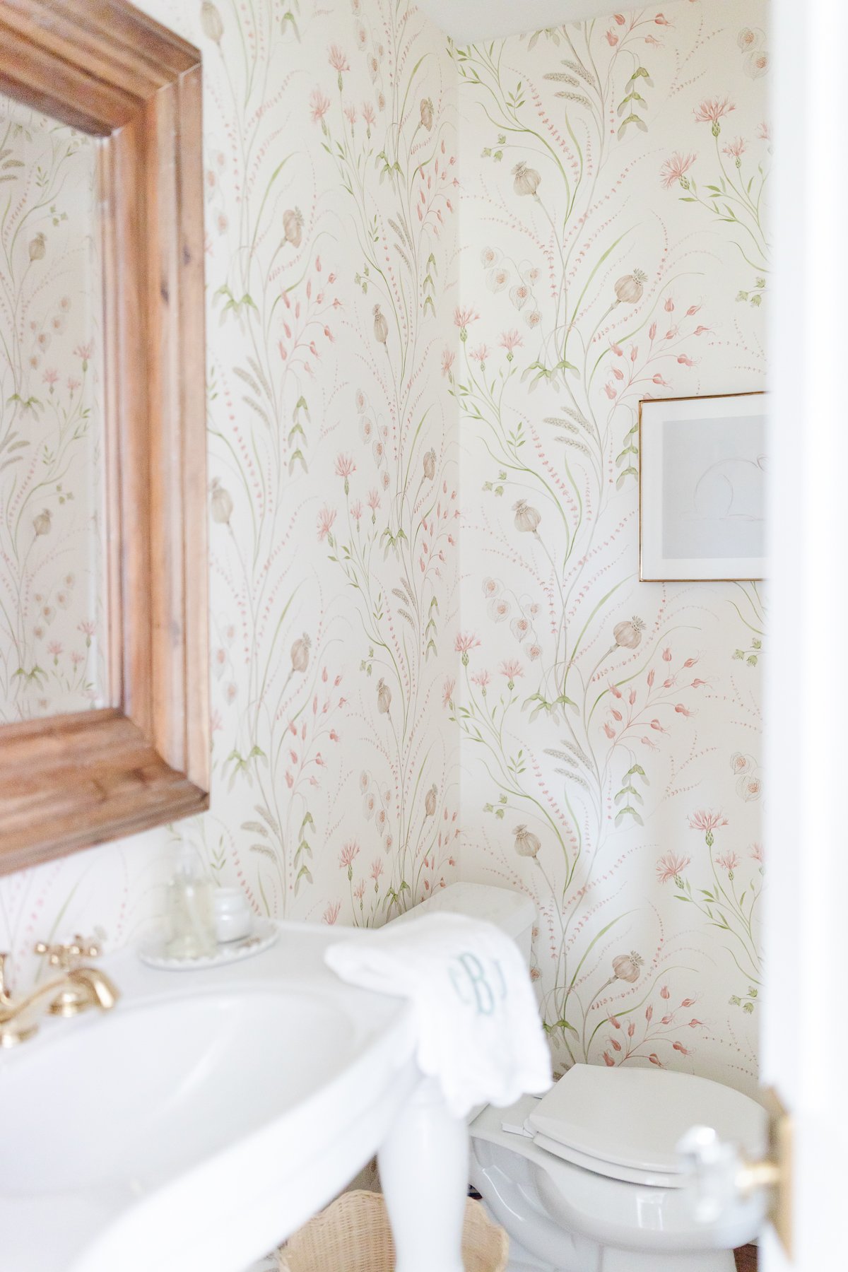 A white pedestal sink with powder room wallpaper in a guest bath