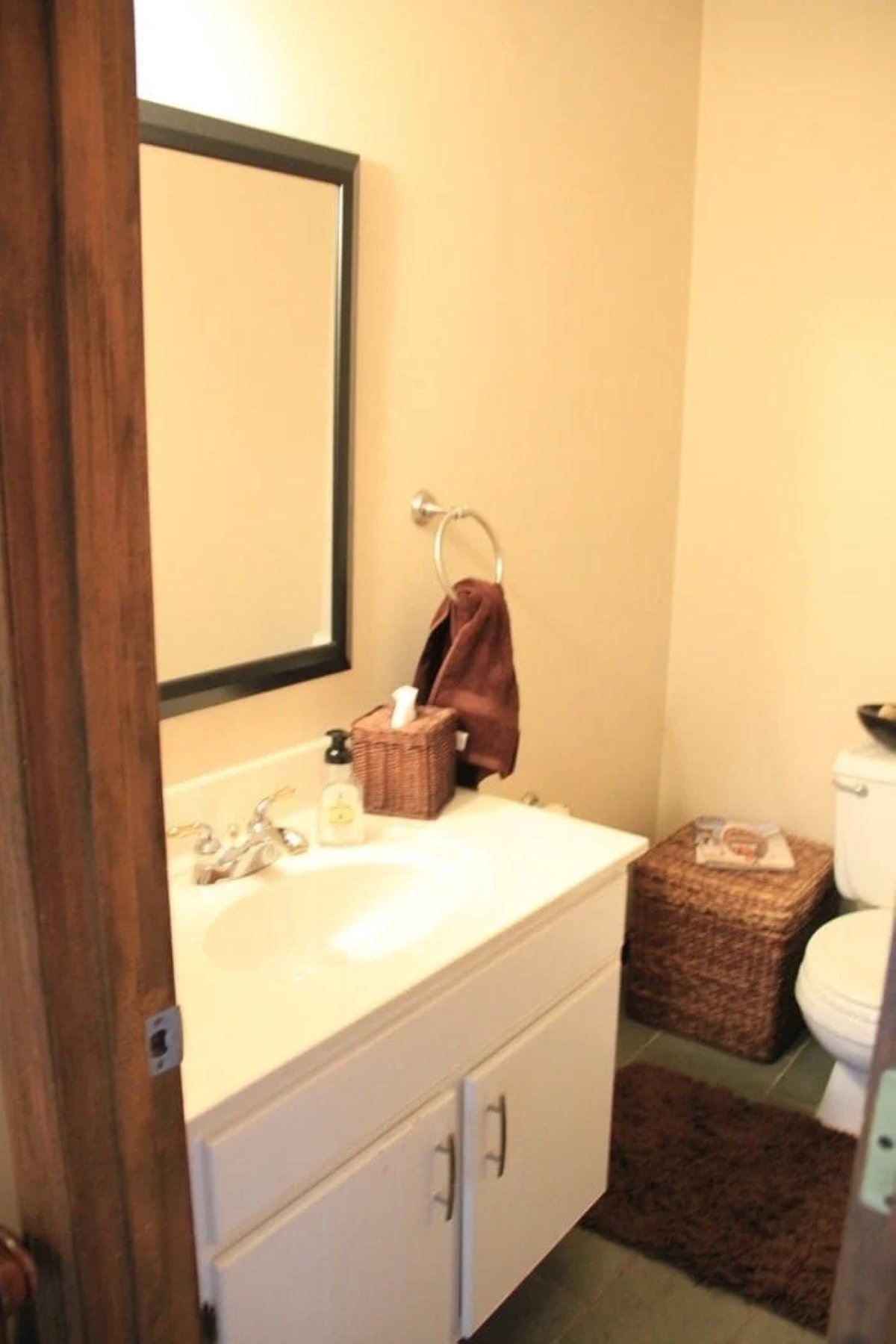 A dark and dated 70's powder room with a white vanity. 